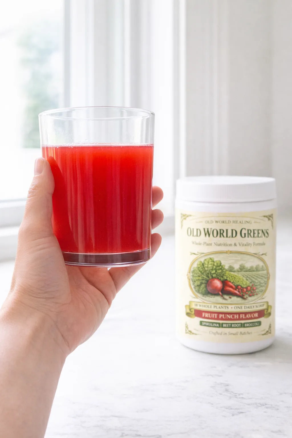 A glass of stirred fruit punch red liquid held to the window