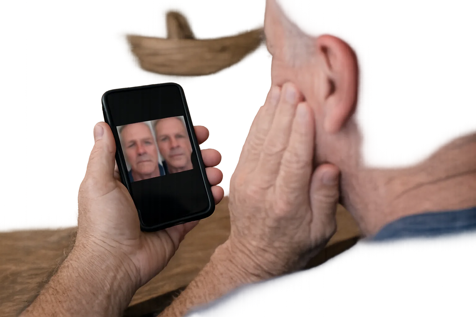 Over-the-shoulder phone photo of a man in his sixties comparing two pictures of his own face two years apart