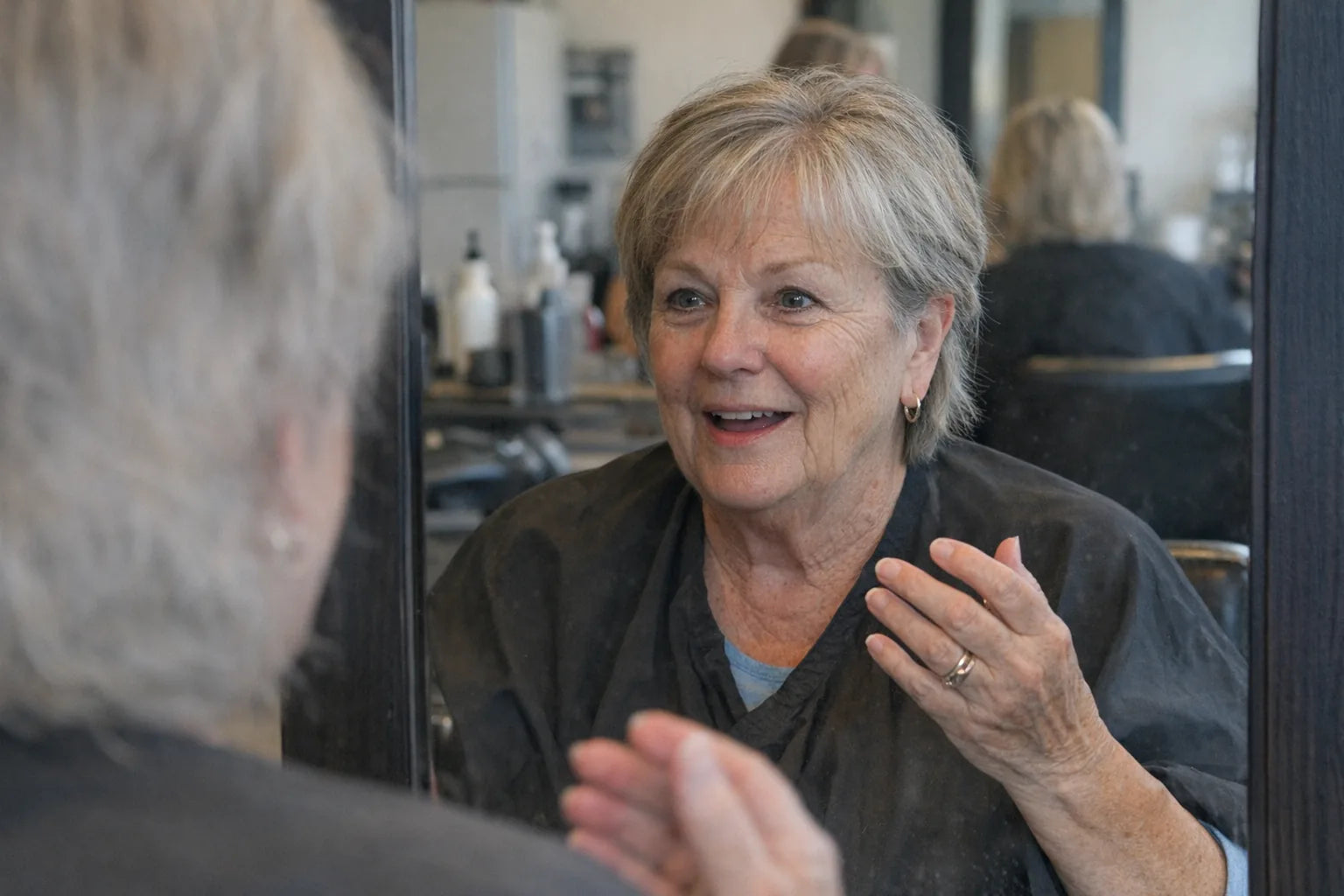 A woman in her mid-sixties in a hairdresser's chair catching her own eye in the mirror