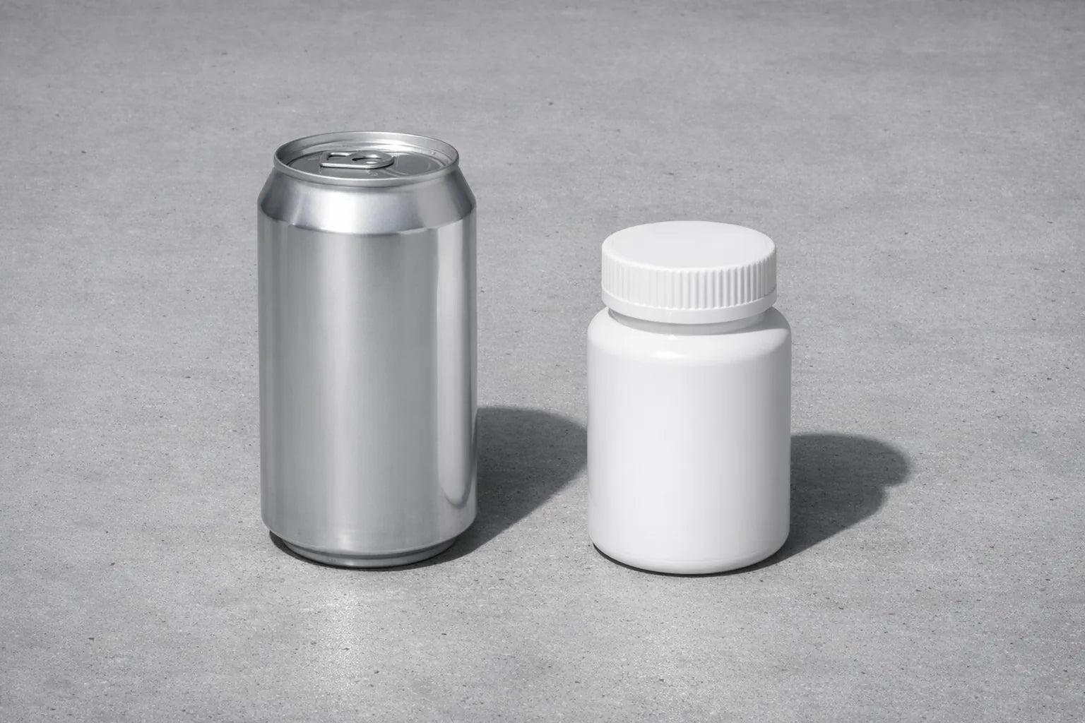 An unbranded energy can and a plain white stimulant pill bottle on a cold grey surface