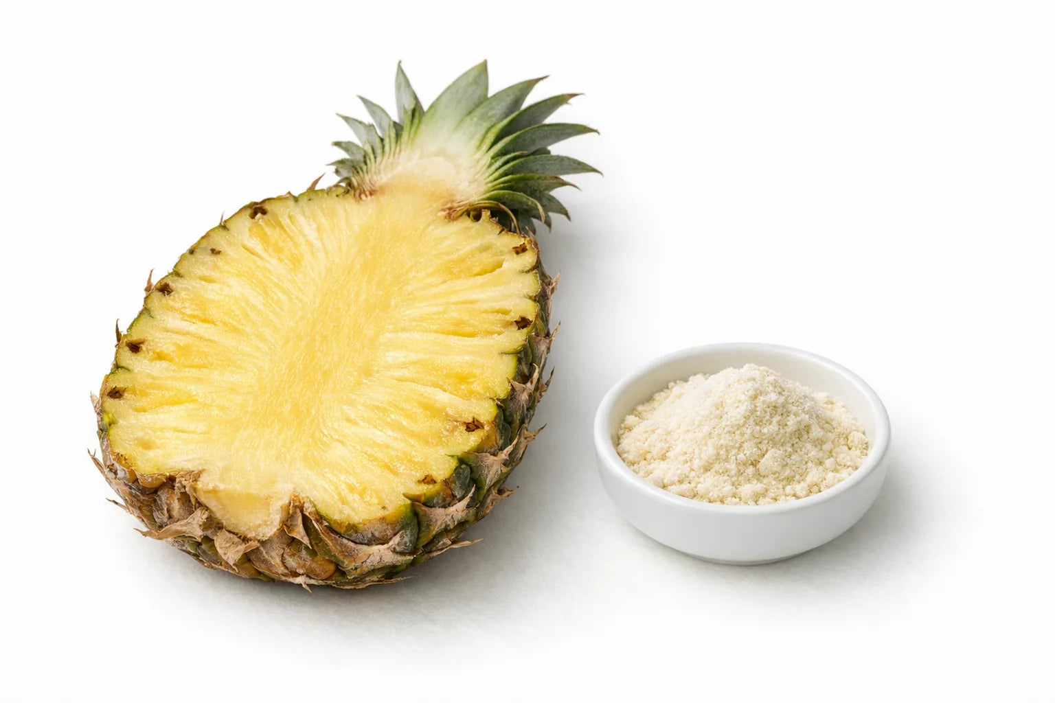A cut pineapple showing its fibrous golden core beside a dish of pale enzyme powder